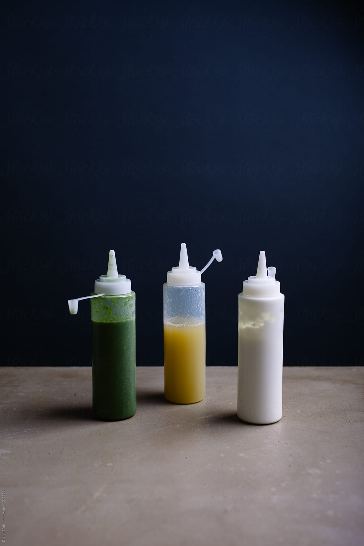 Three different types of sauces in squeeze bottles.