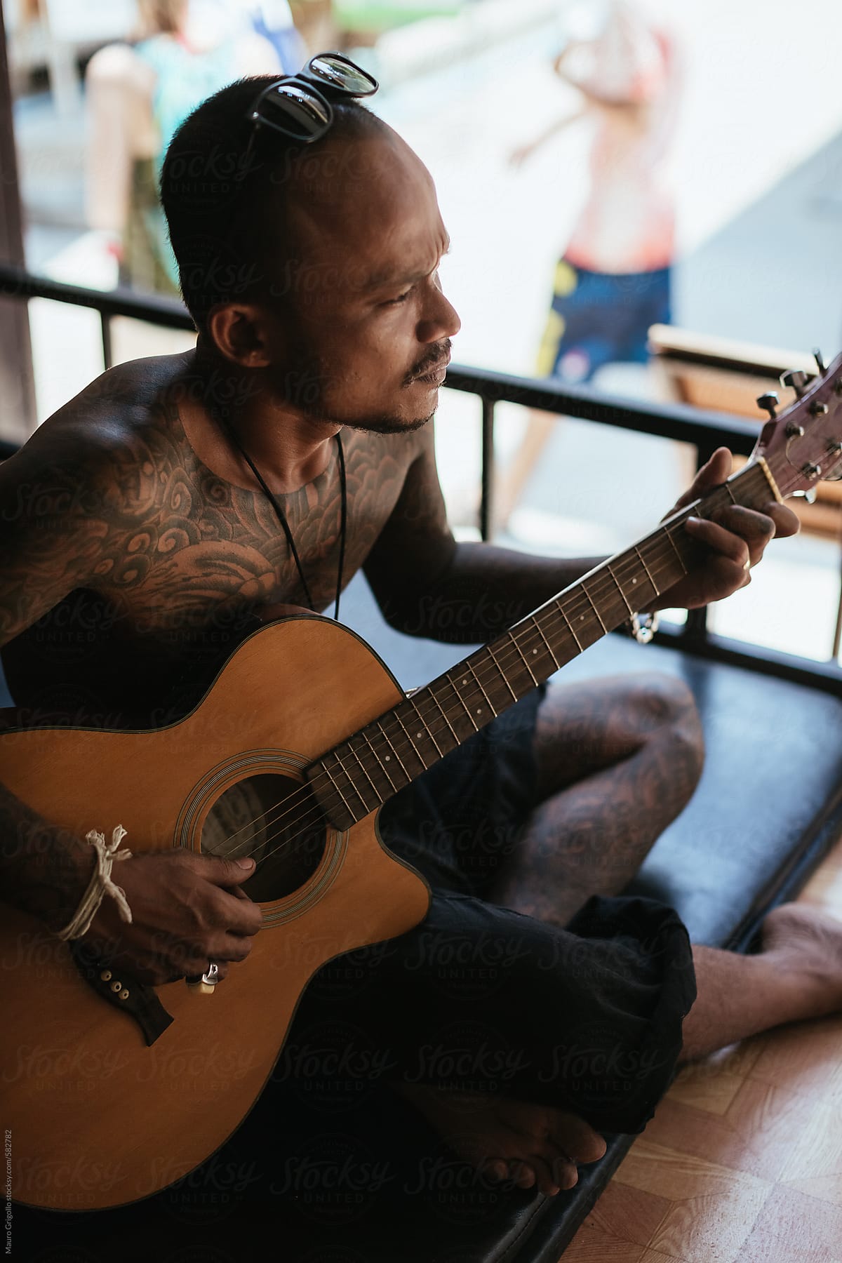 Thai tattoo artist playing guitar during a break.