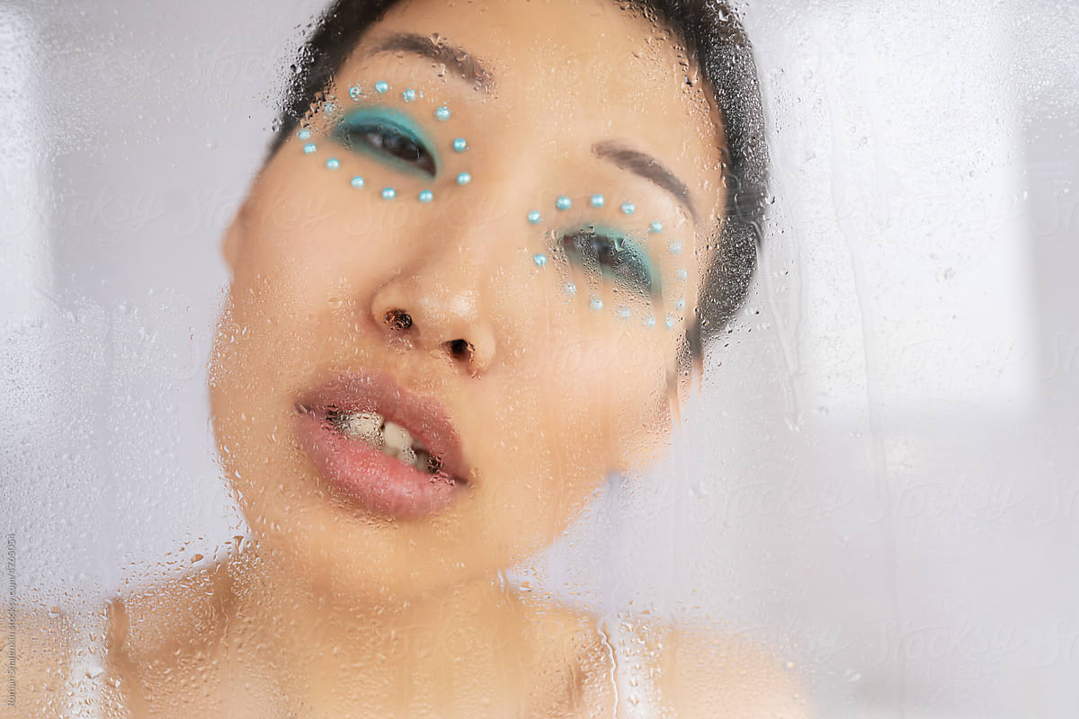 Through wet glass of Asian woman