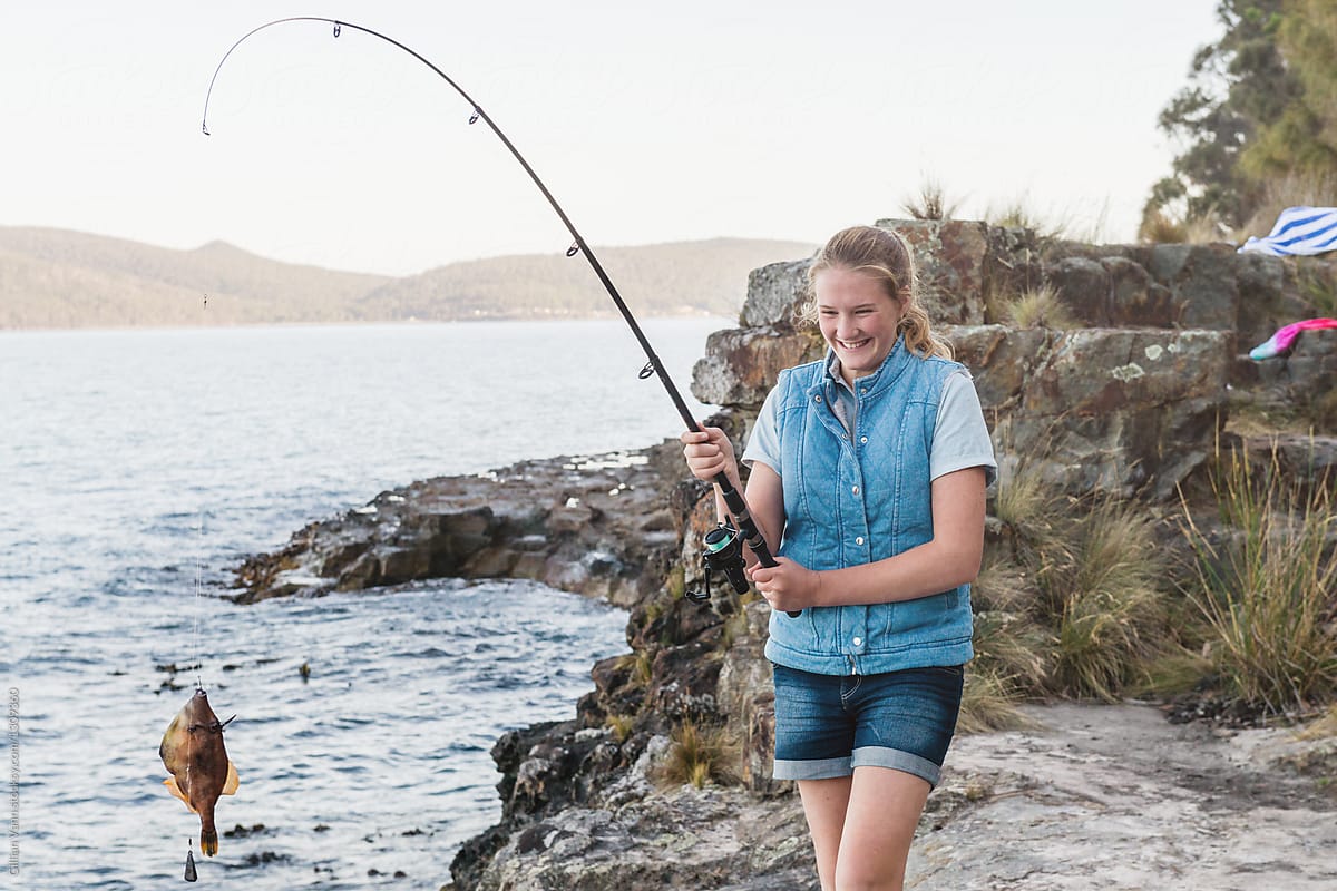 Happy Teen Girl Fishing, With A Leatherjacket Fish On The Line by Stocksy  Contributor Gillian Vann - Stocksy