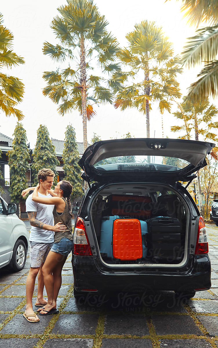 couple hugging by car full of luggage