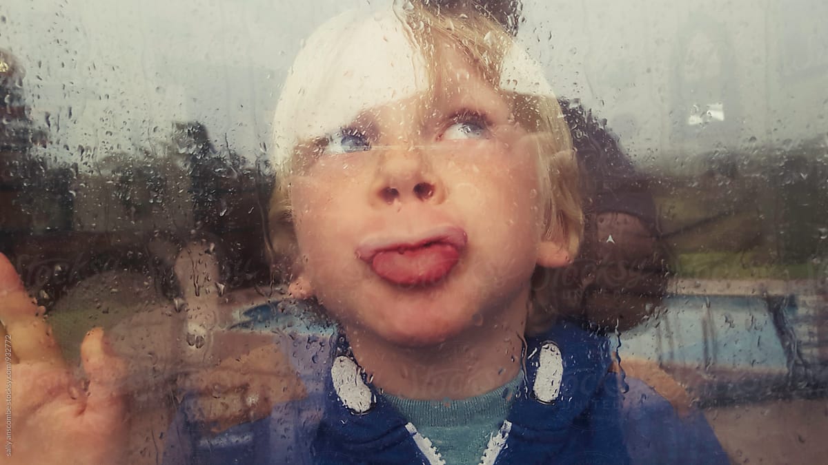 Child looking out of the window on a rainy day