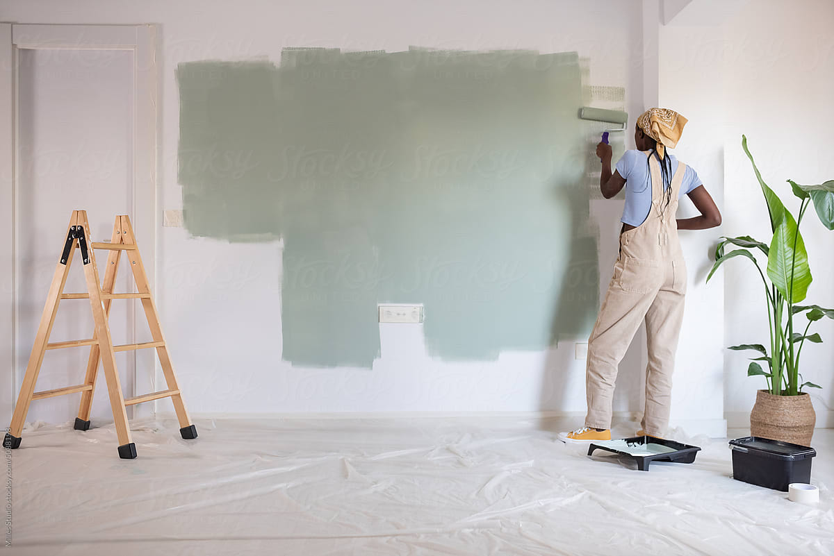 Black painter renovating light room at home