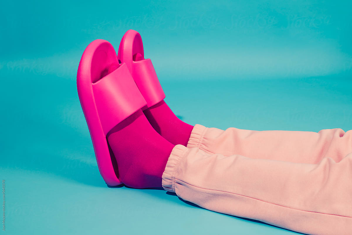 man wearing pink socks and sandals laying on a blue background