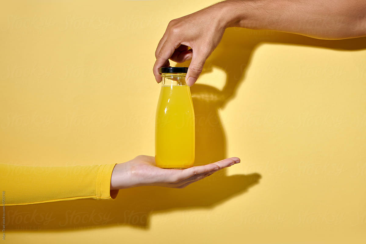 Female hand with bottle of juice on color background