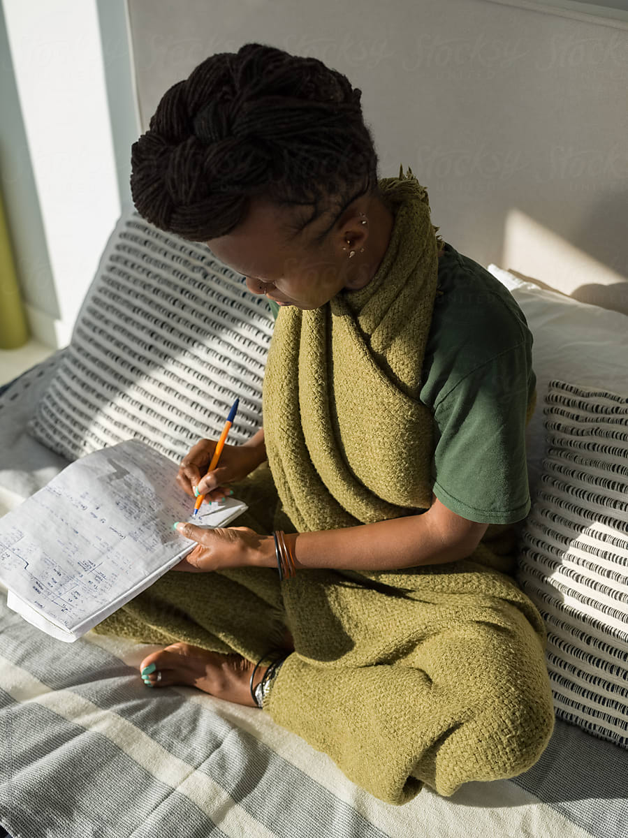Black woman writing notes while studying language