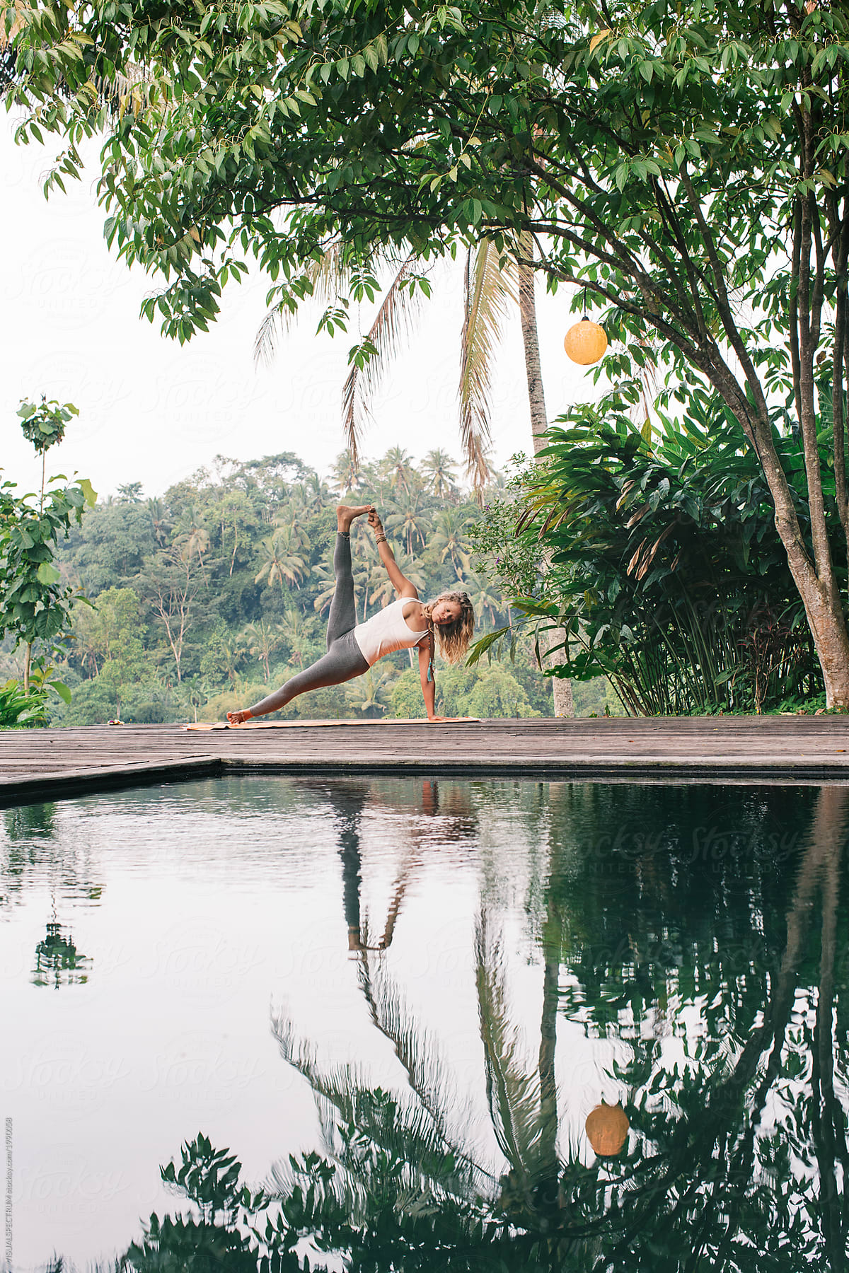 Female Yoga Practitioner Doing Asana Practice by Pool in Tropics