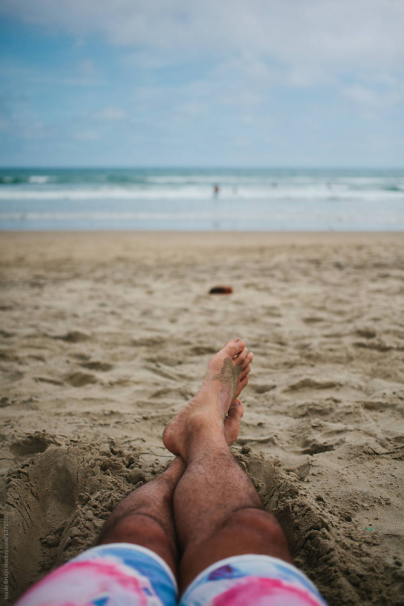 Legs of someone lying on the beach and the ocean