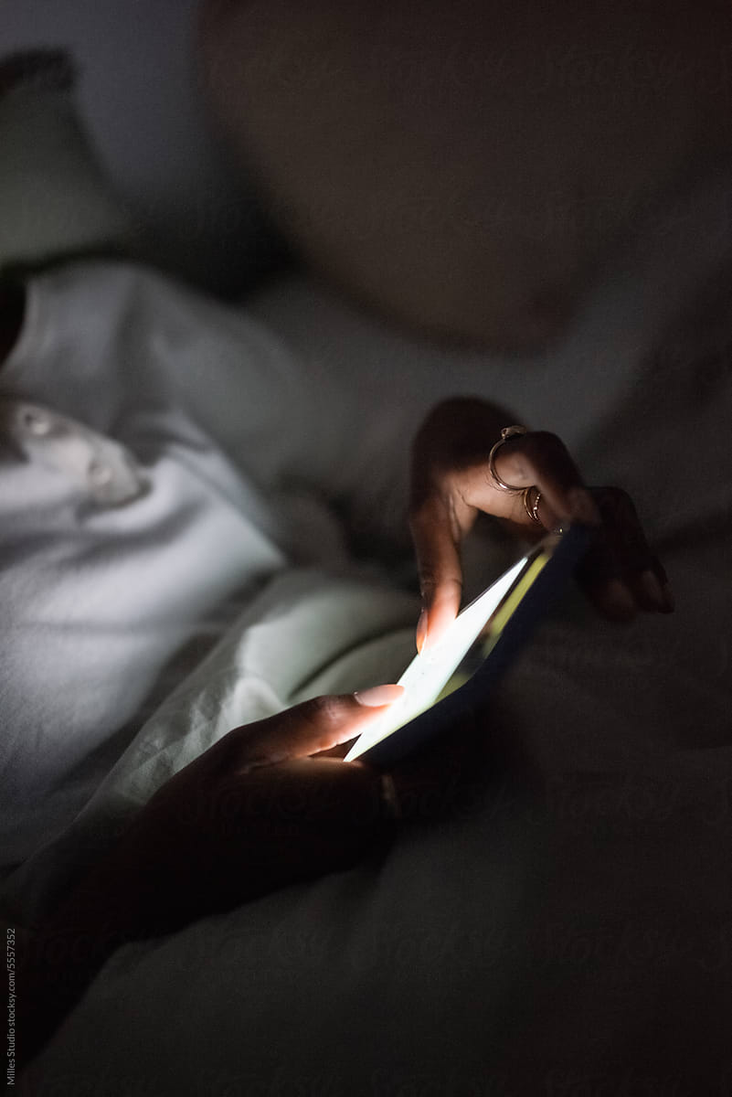 Crop woman chatting via cellphone at night