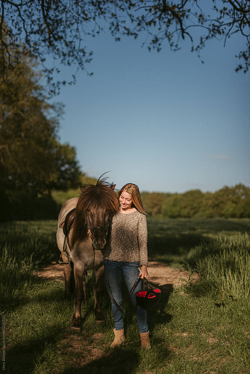 Equestrienne and horse standing in field