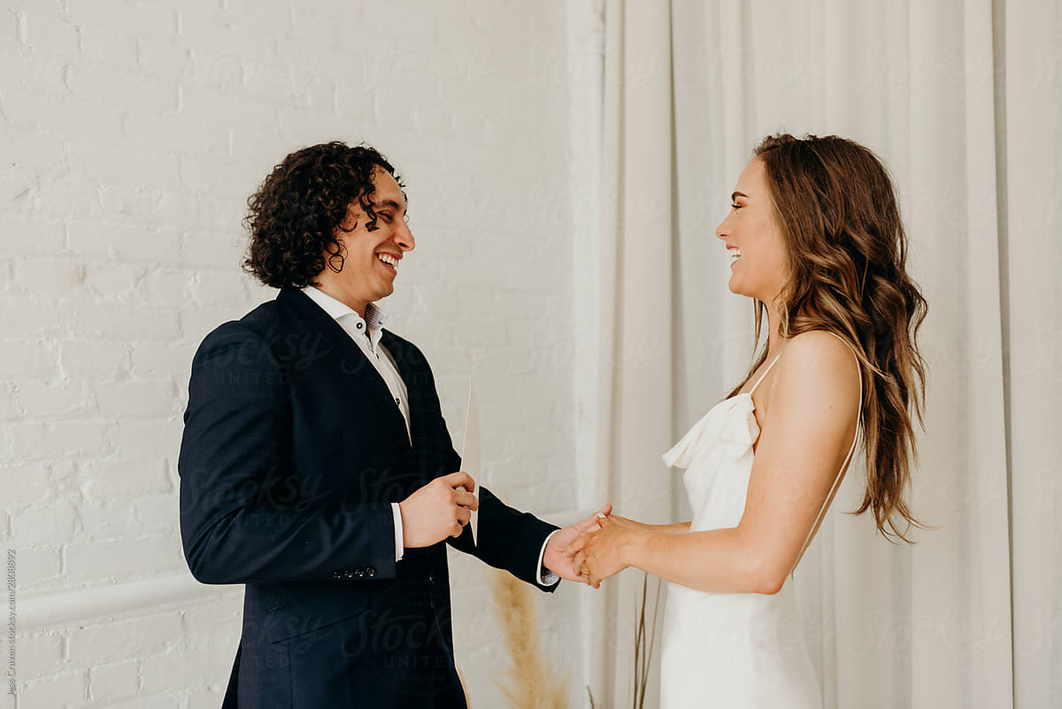 Interracial couple exchanging vows in minimalist white loft