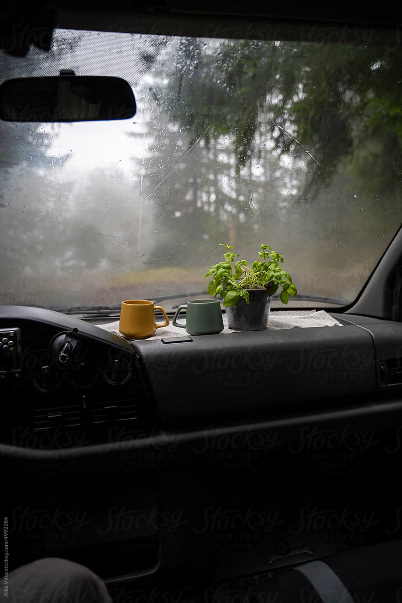 Coffee cup inside camper van on a rainy day