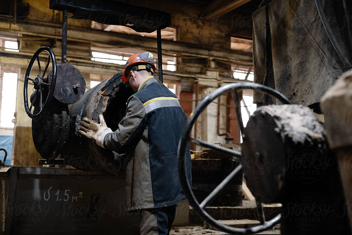 Male worker cleaning crucible in foundry