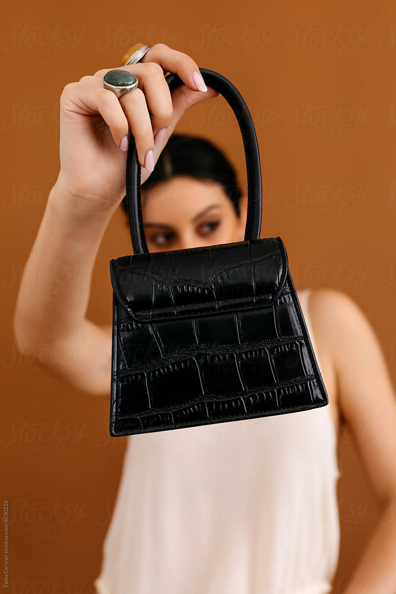 Confident lady in studio showing black leather purse