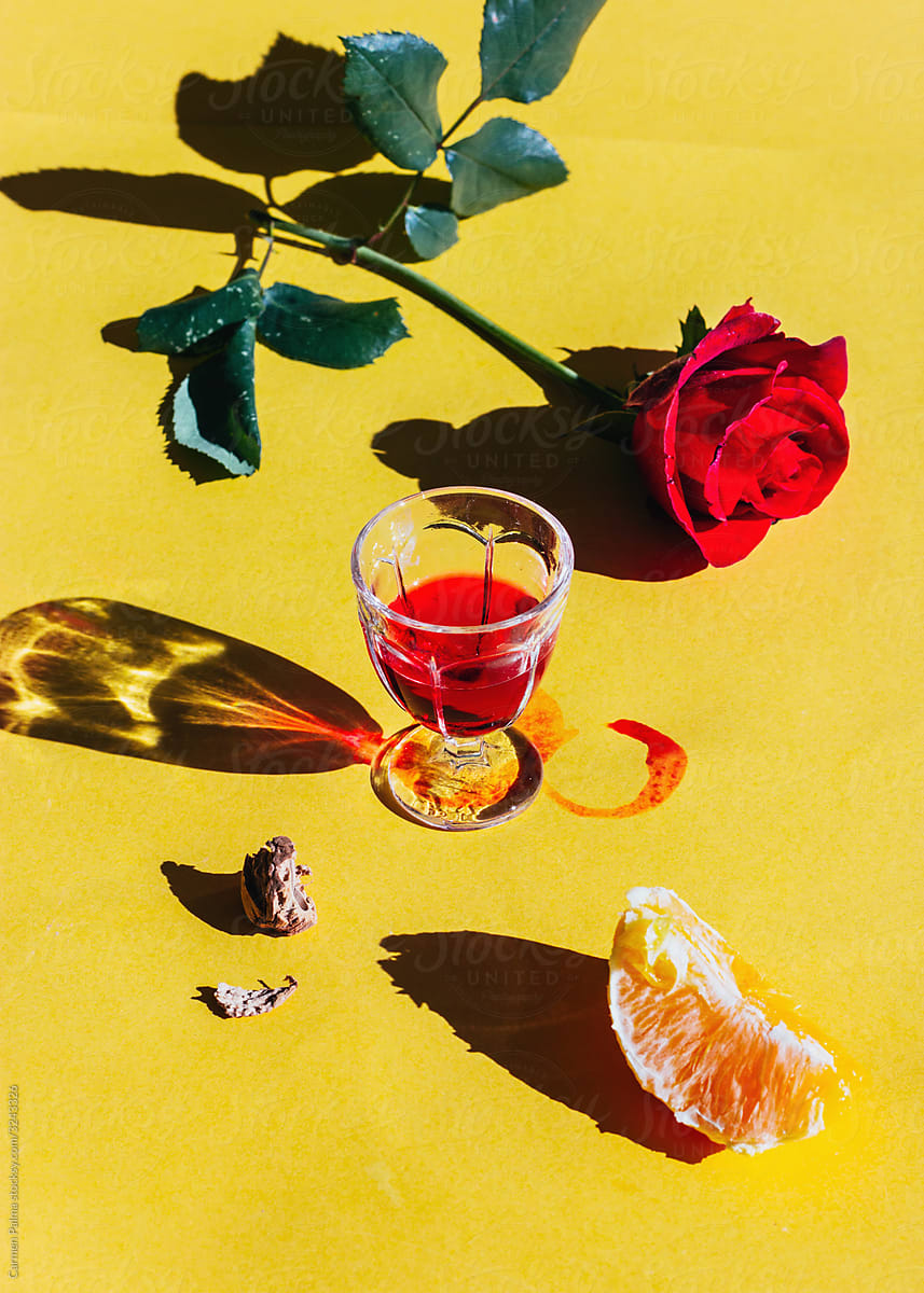 A red liquor glass, an orange slice and a red rose.