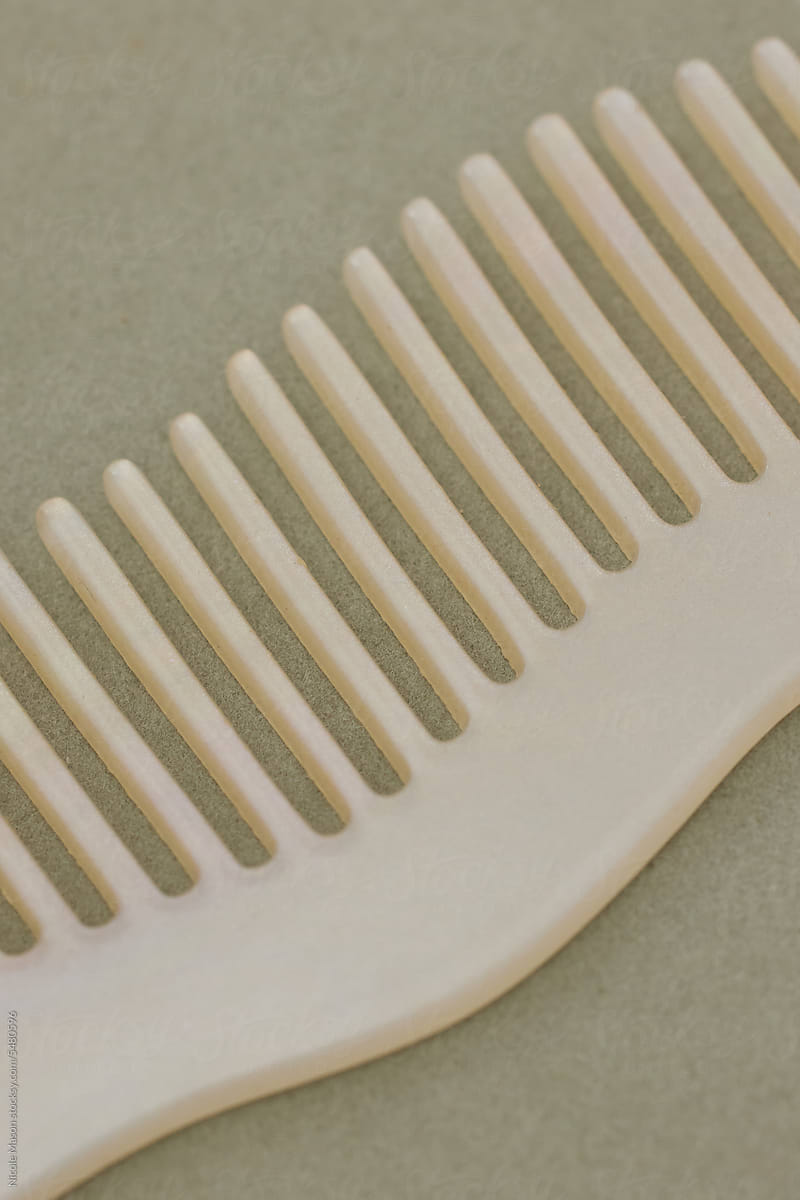 Macro of Curvy Cream-Colored Comb on Sage Surface
