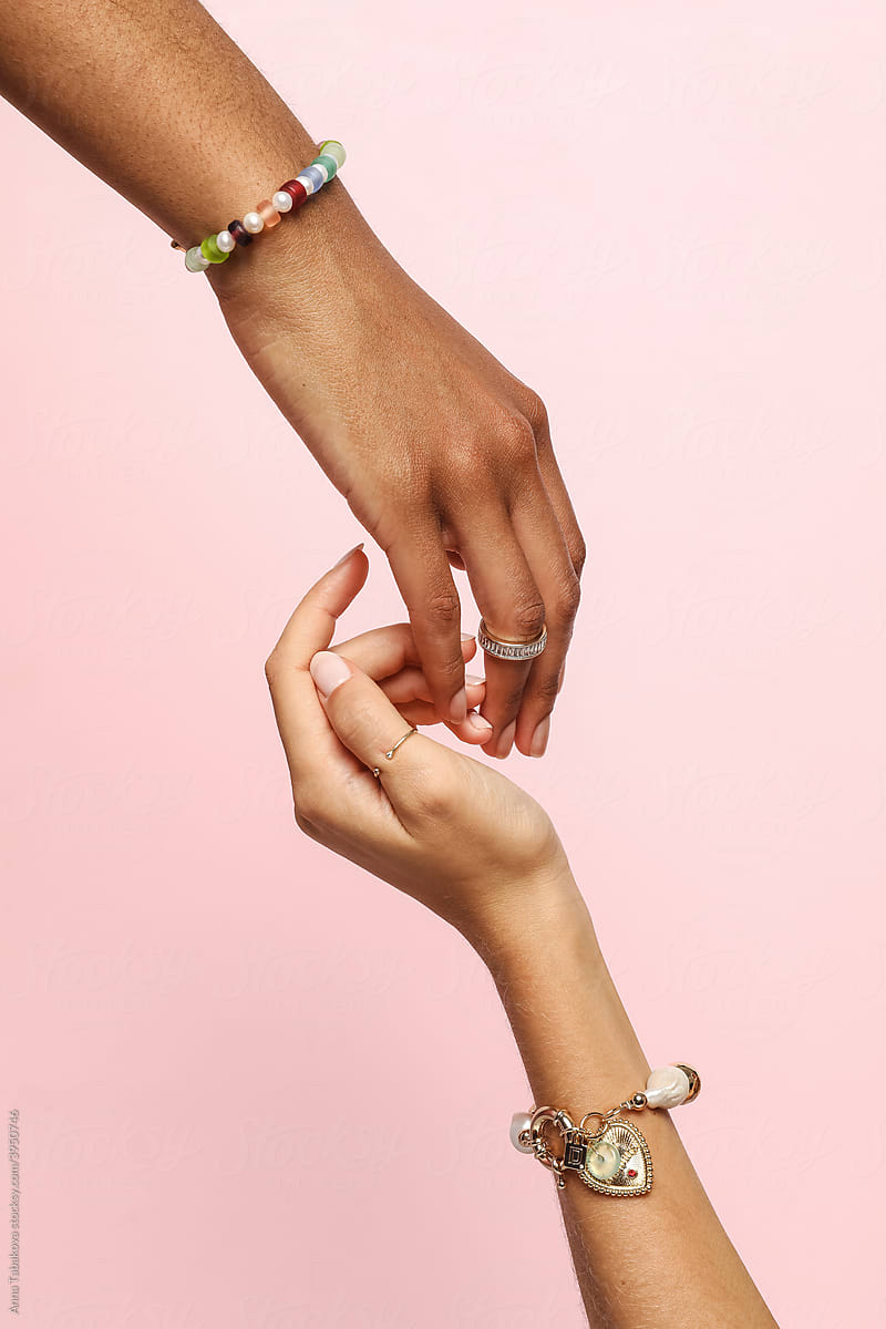 Two female hands with jewelry on holding each other