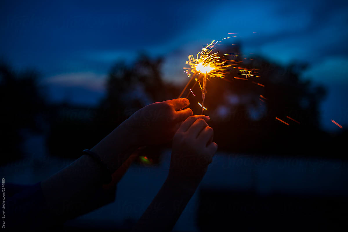 Woman\'s Hand Holding Sparkler To The Sky At Twilight