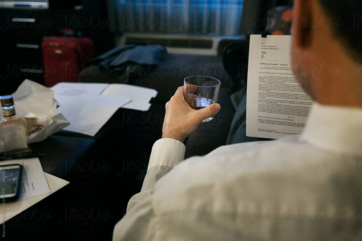 Business: Businessman Has Drink While Reviewing Contract
