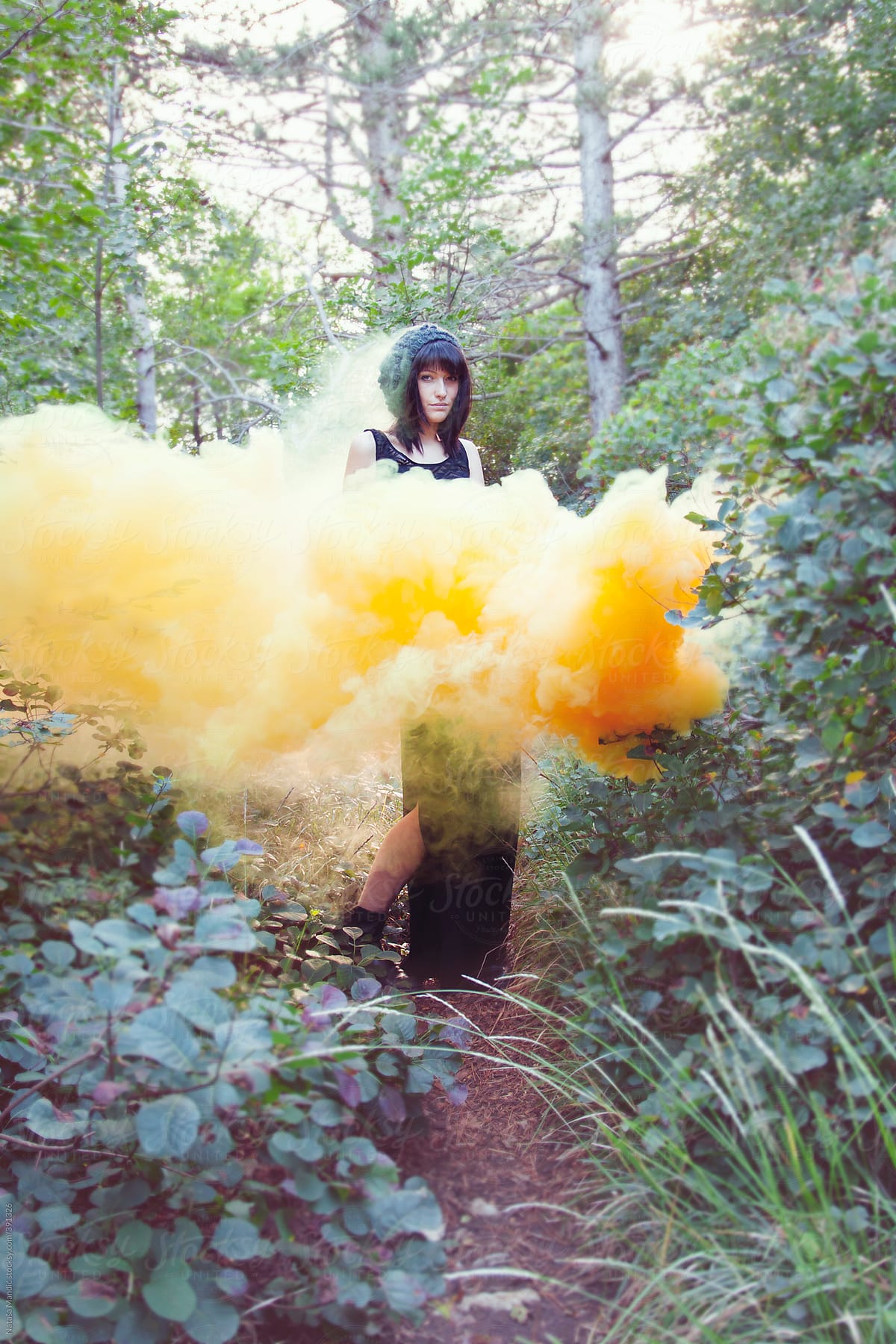Beautiful woman standing in yellow smoke in the forest