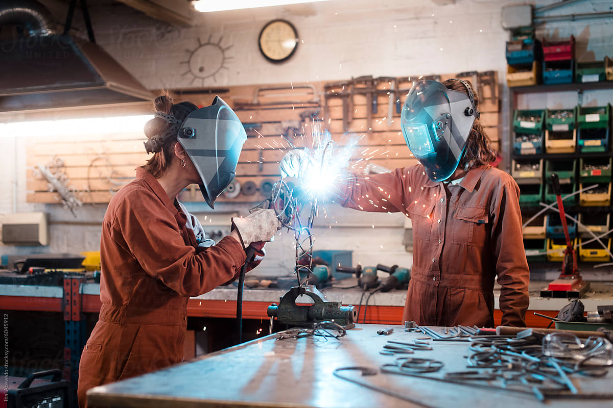 Artists welding iron sculpture at workshop