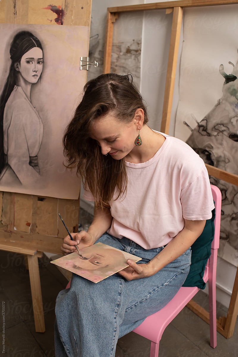 Painter in pink surrounded by her art pieces