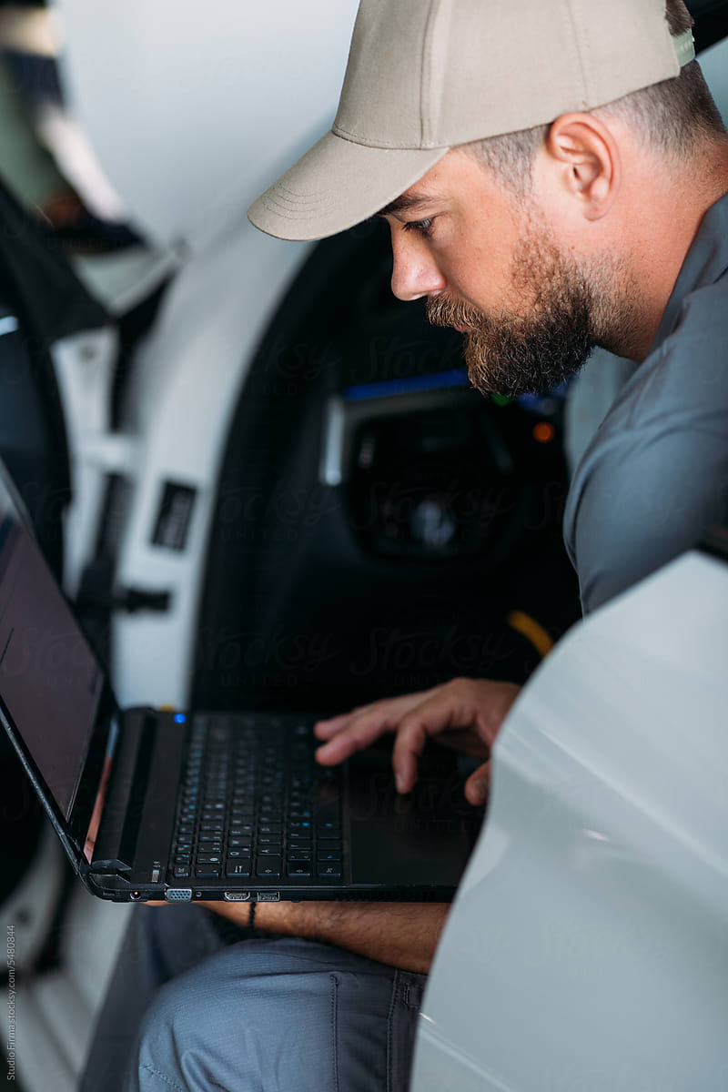 Man Working in Garage, Using Laptop for Diagnostic