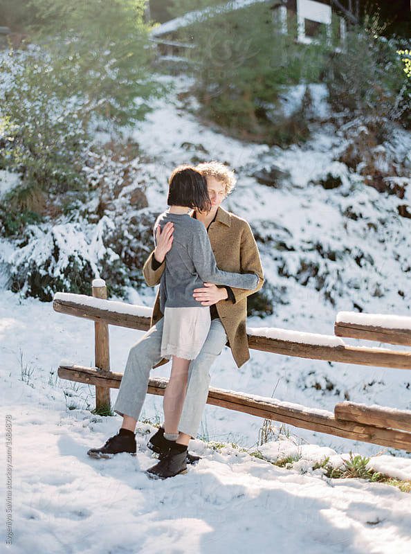 A portrait of a young couple cuddling in the morning light in winter forest