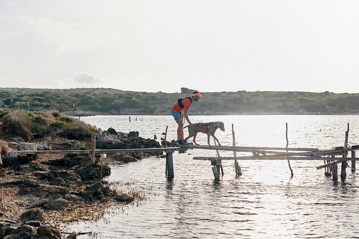 Man and his dog walking on a jetty