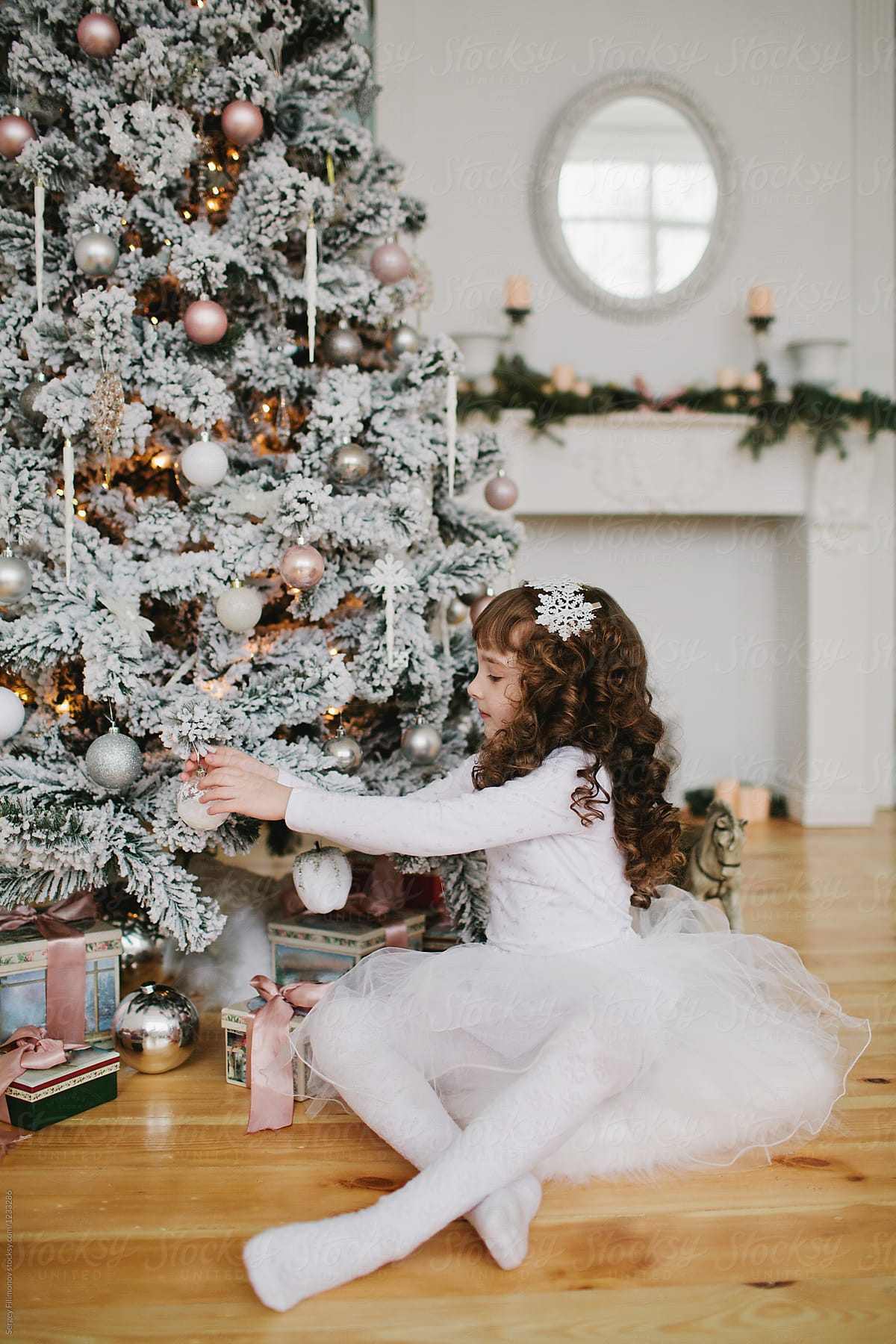 Girl decorating white Christmas tree