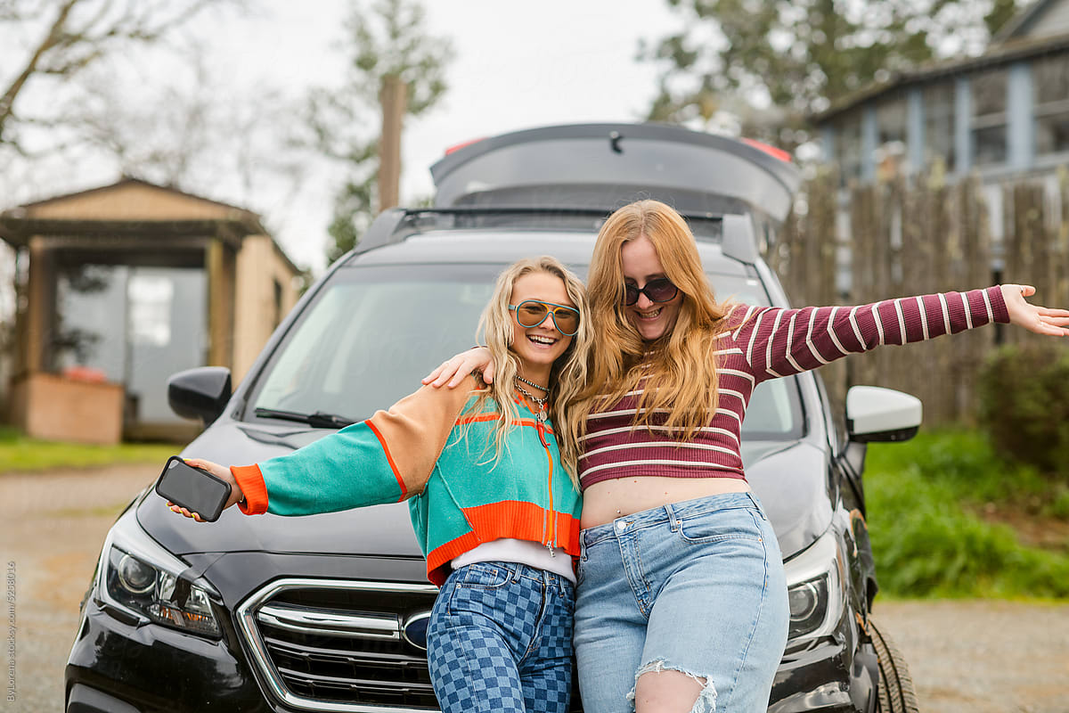 Portrait of excited traveling female friends with car