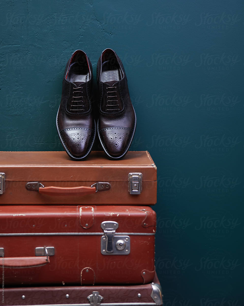 Handmade leather men\'s shoes stand on vintage suitcases