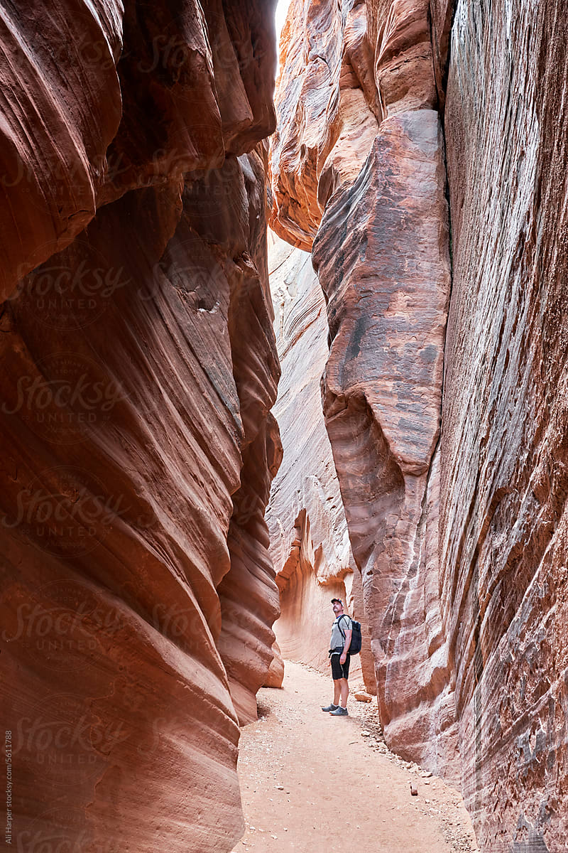 Man hiking within the undulating rock formations of Bulkskin Gulch