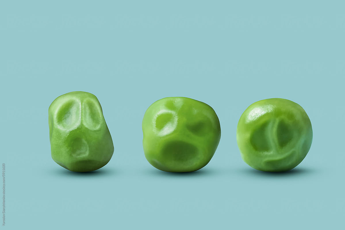 Three green peas showing different grimaces over blue background