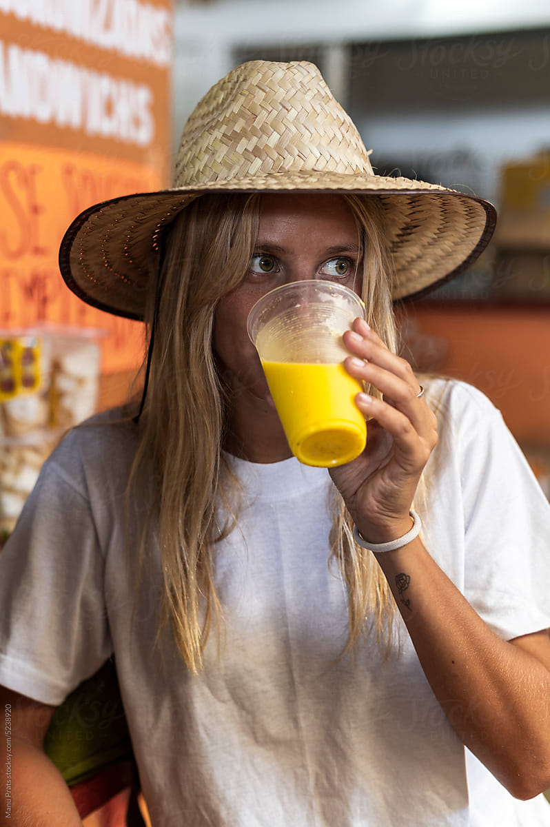 Woman traveler drinking fresh fruit juice in market