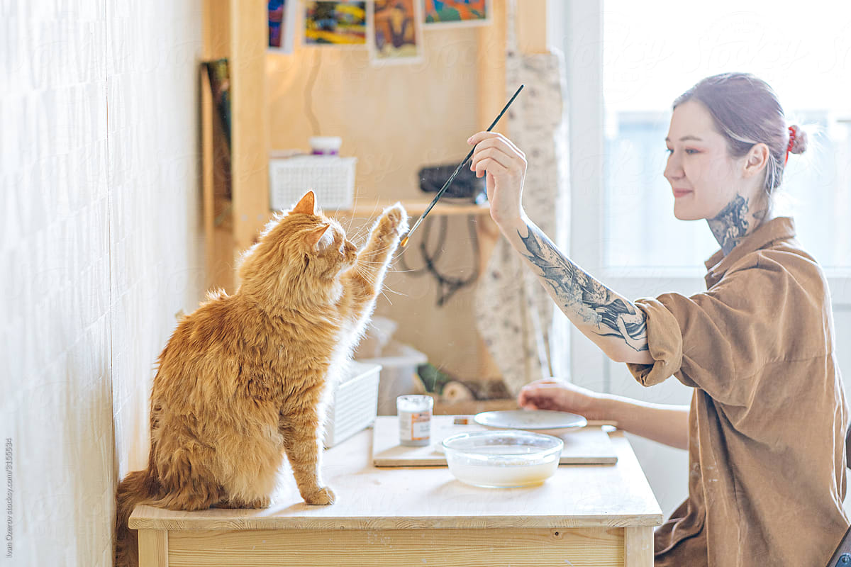 girl playing with her cat while working