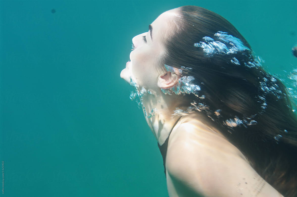 Brunette woman swimming forward with bubbles