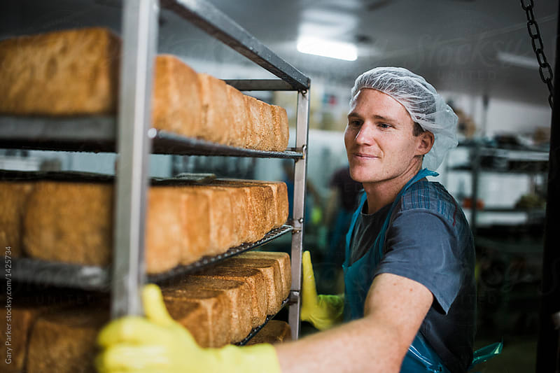 A baker carting a freshly baked rack of spouted bread