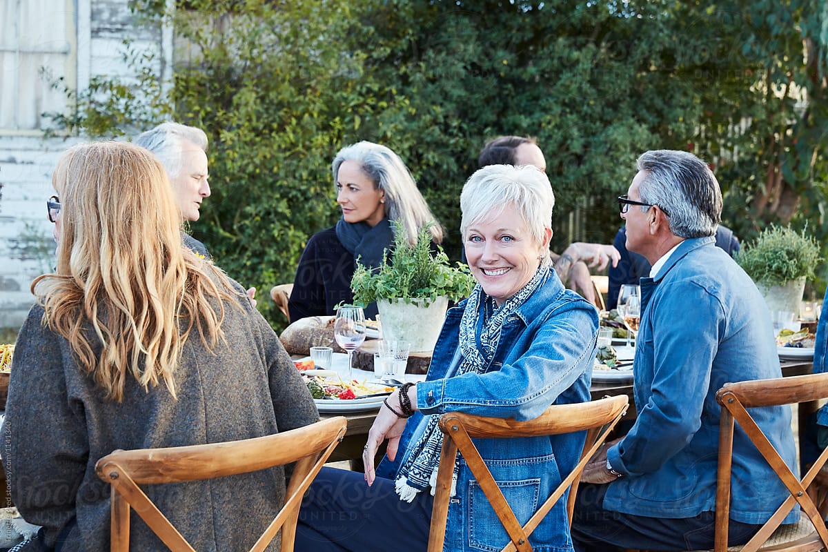 Portrait of Senior woman with group of friends enjoying a farm to table dinner party