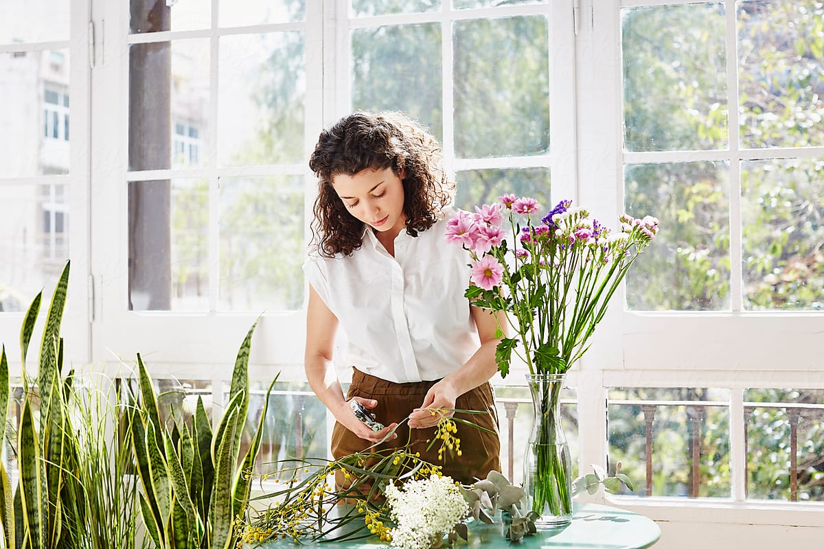 Woman Trimming Plants By Flower Vase At Home
