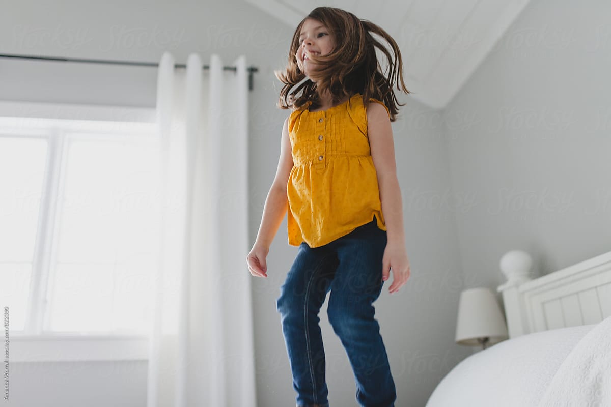 Happy, smiling girl jumping on bed, movement