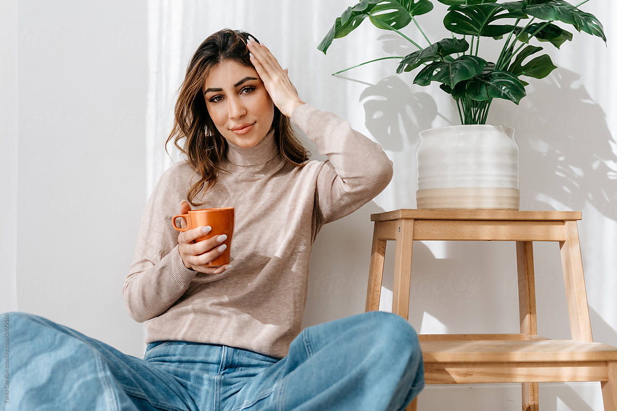 Content woman sitting on floor with mug of coffee