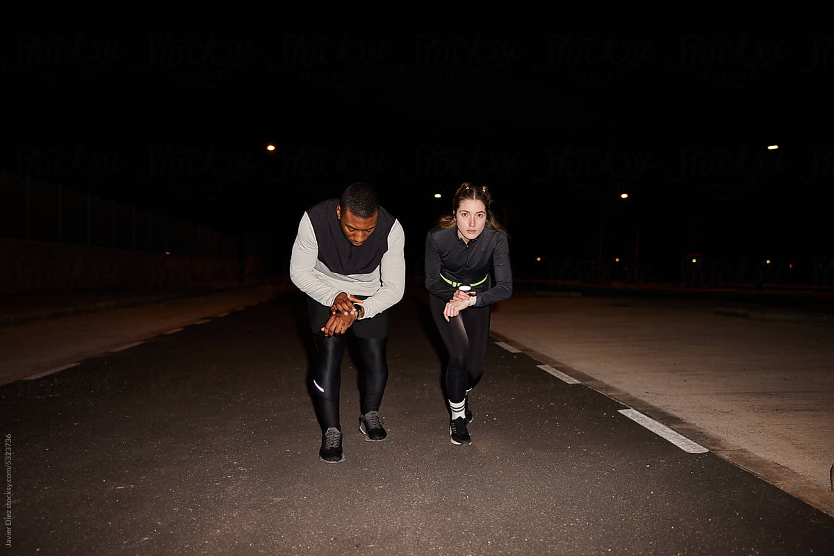 Fit multiracial people ready to run on street at night