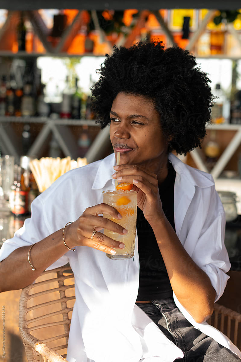Black woman drinking cocktail in a bar