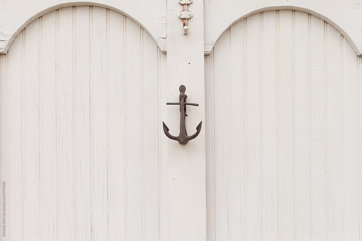 Horizontal detail of a painted white door with bead board details and an anchor door knocker