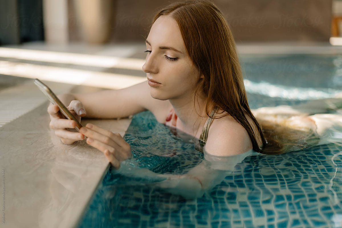 Female with smartphone relax in pool