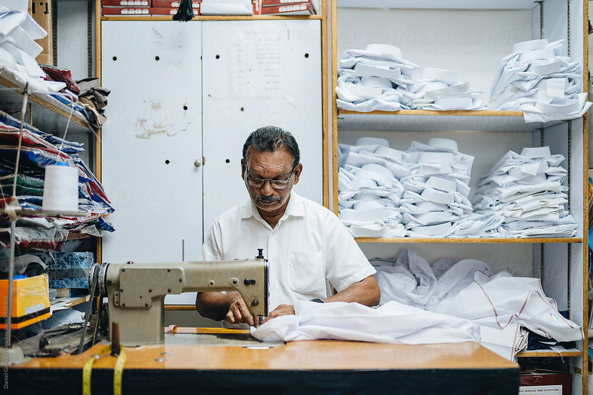 Calm Indian tailor sewing in atelier with fabric