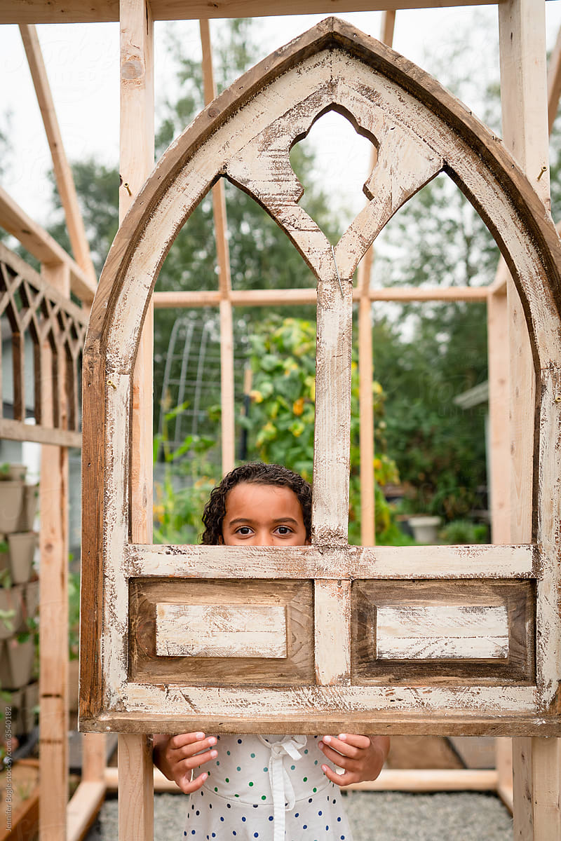 girl peeking through old church window frame