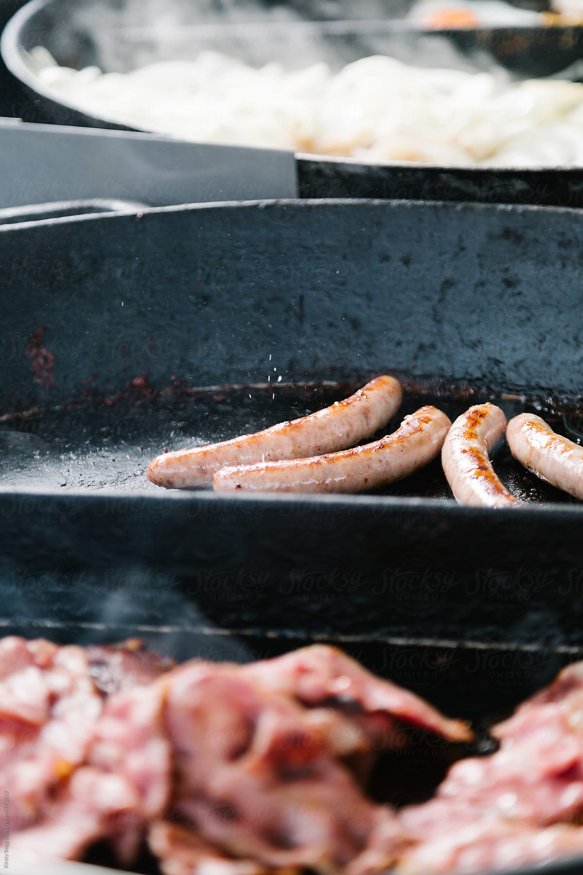 Sizzling sausages in cast iron pan at street market