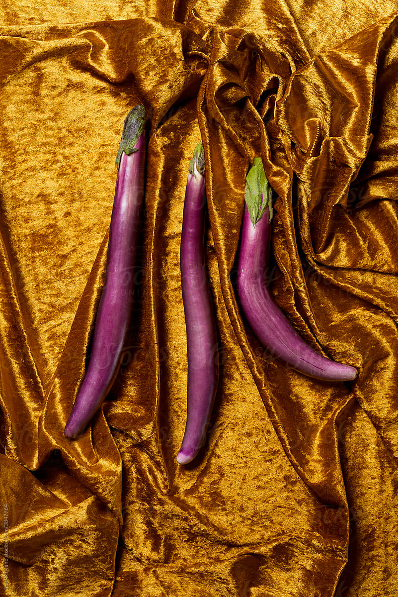 purple japanese eggplants on a golden fabric